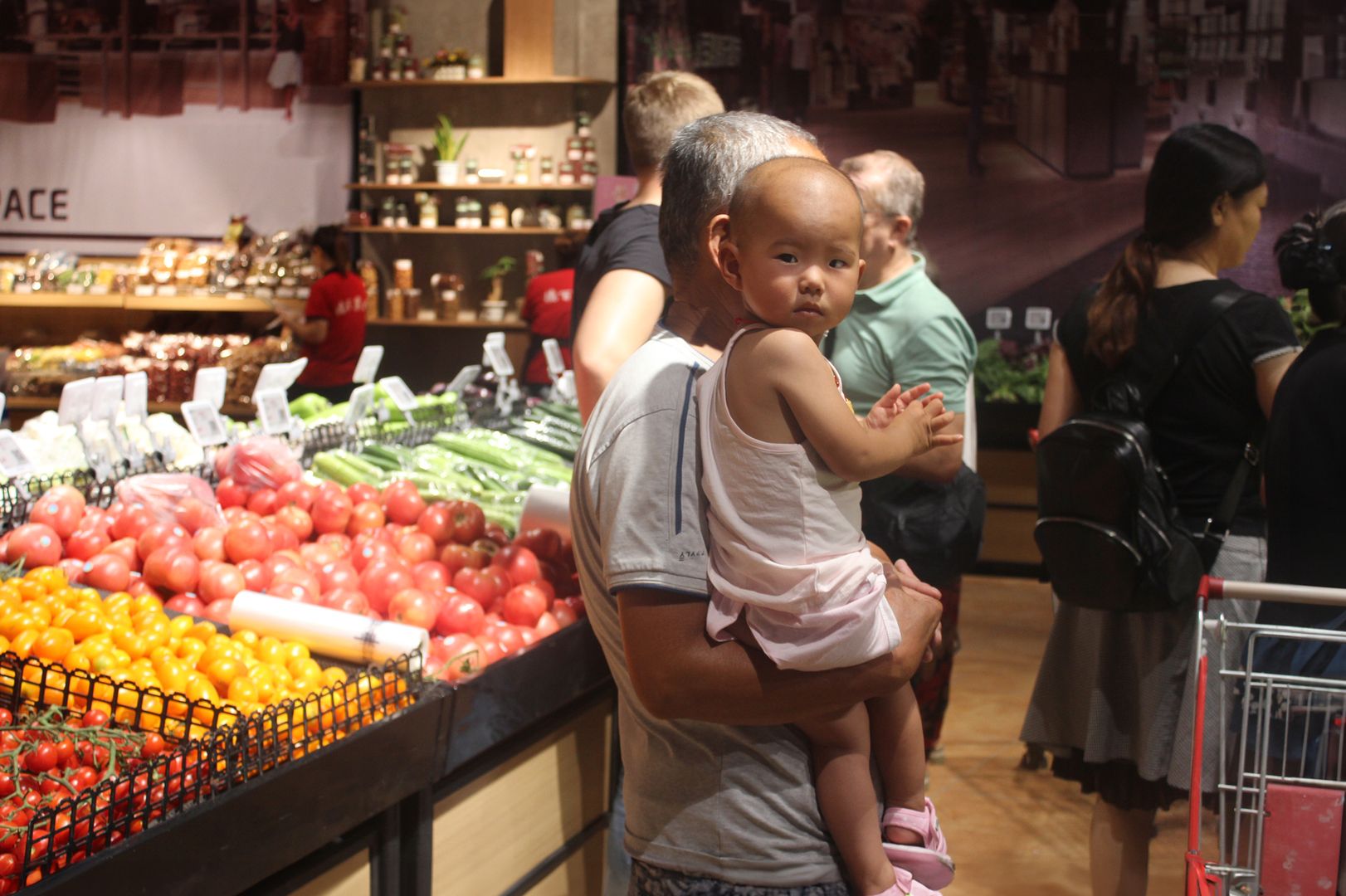 A grocery store scene with a selection of fresh vegetables and fruits, with shoppers strolling through the aisles.